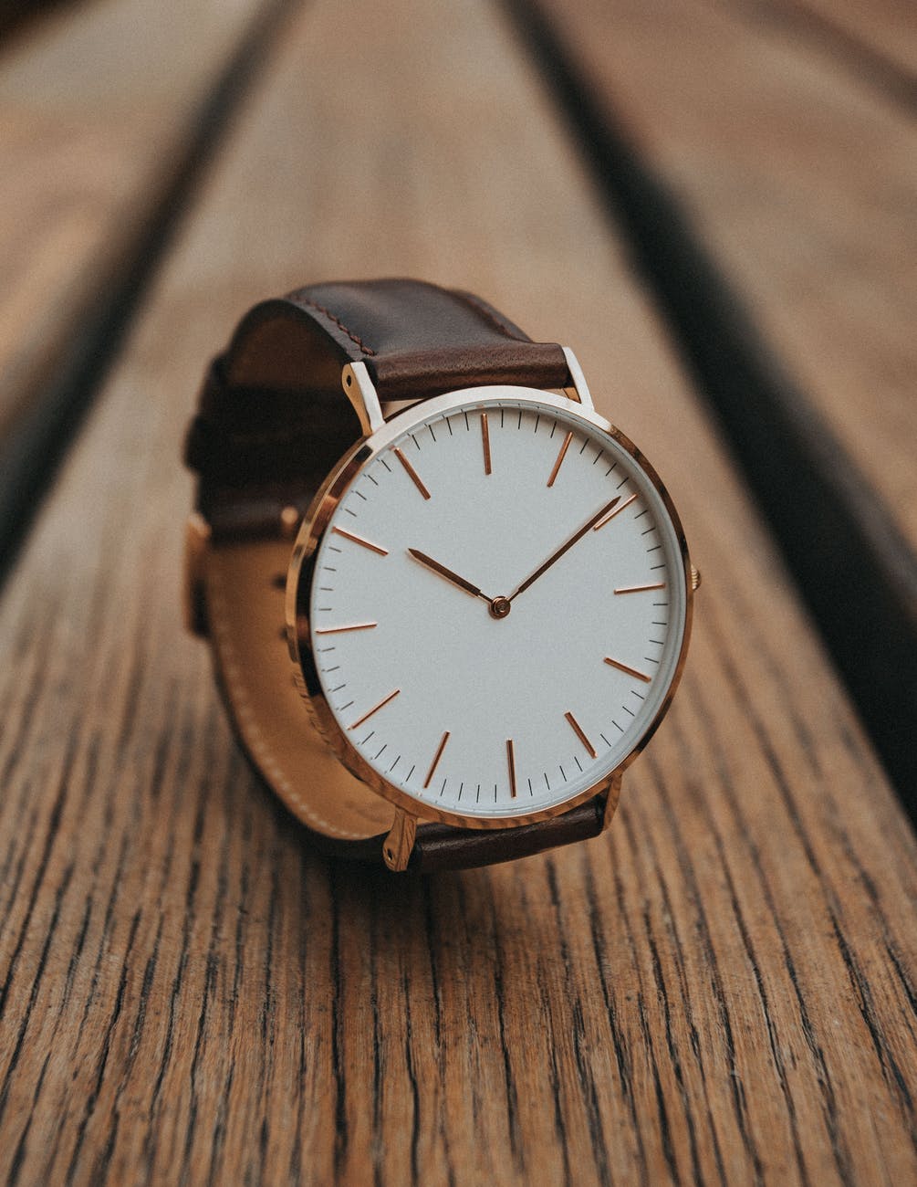 round gold analog watch with brown leather strap